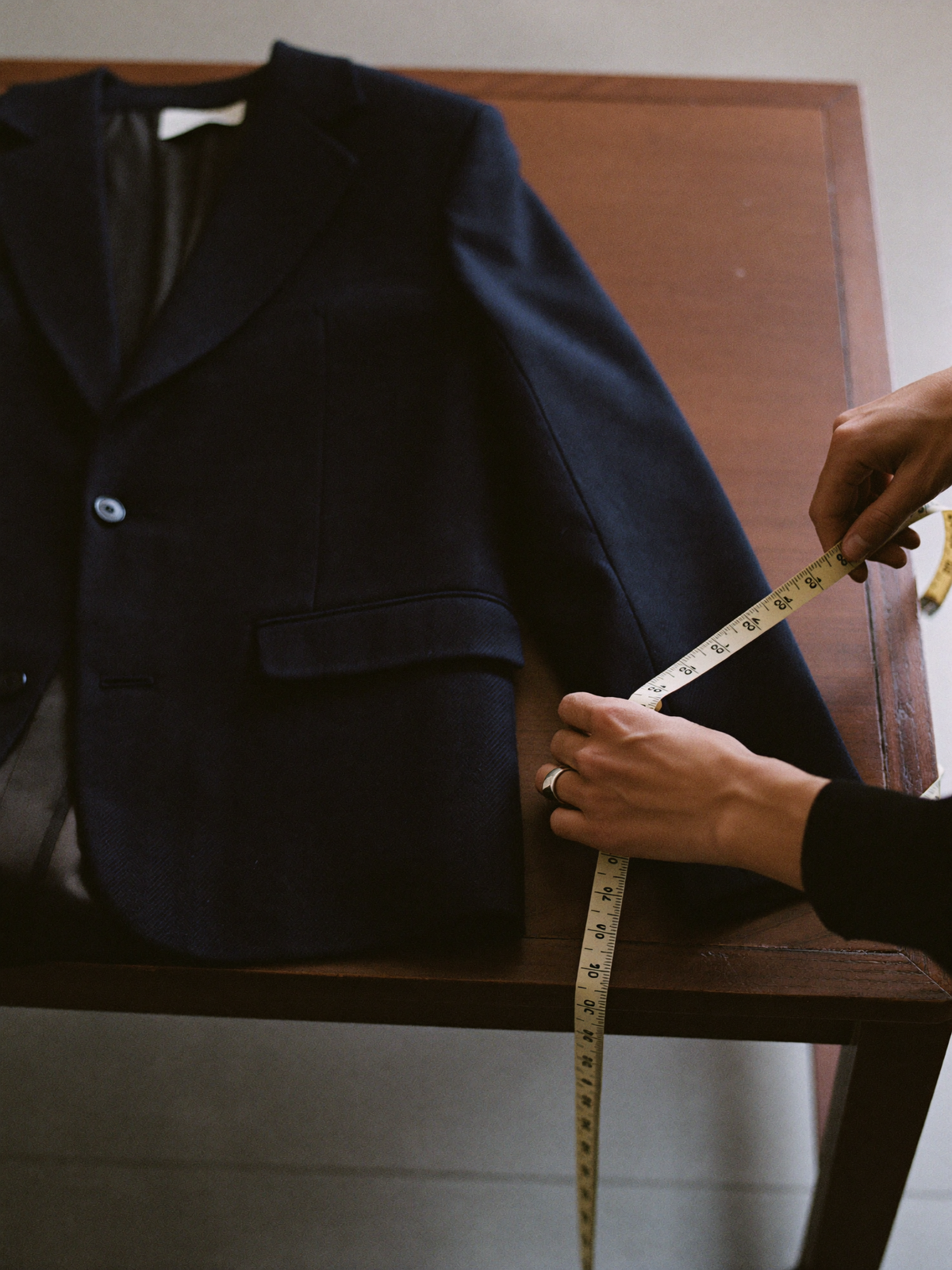 A tailor measuring a jacket sleeve